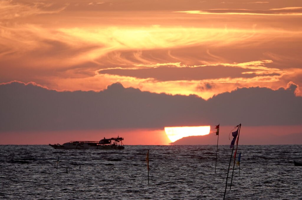Clouds glow brightly in the light of the sun setting on the horizon.