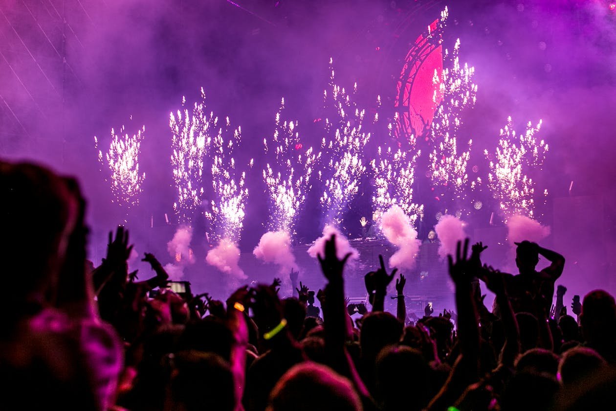Crowd enjoying outdoor music festival with colorful stage lights at night