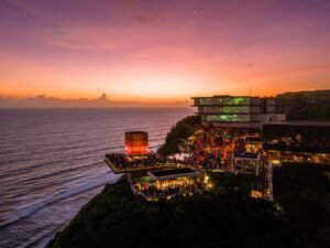 Savaya Bali in Uluwatu at sunset, the illuminated Cube stage and packed clifftop terraces above the Indian Ocean