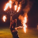 Fire performers spinning flames at night at the Believe In Destiny Festival in Ubud, Bali
