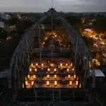 Aerial view of the Jia CURATED design festival in Bali at dusk, a large lit timber pavilion with market stalls strung with lights