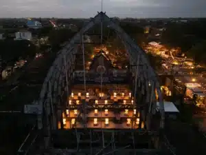 Aerial view of the Jia CURATED design festival in Bali at dusk, a large lit timber pavilion with market stalls strung with lights