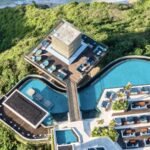 Aerial daytime view of Savaya Bali in Uluwatu showing the Cube, curved clifftop pools, daybeds and the jungle cliff down to the beach