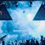 Crowd at night under illuminated triangular LED screens and smoke at Savaya Bali, Uluwatu