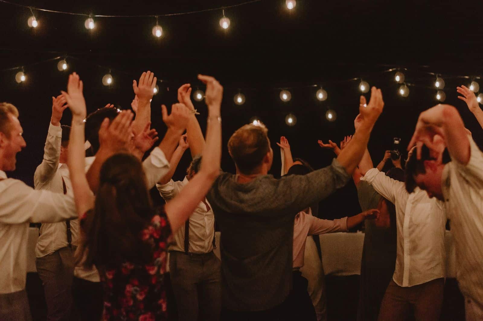 People dancing at an outdoor night party under warm string lights, evoking the Afro and amapiano vibe of Ulu Riddim at Hatch Uluwatu, Bali.